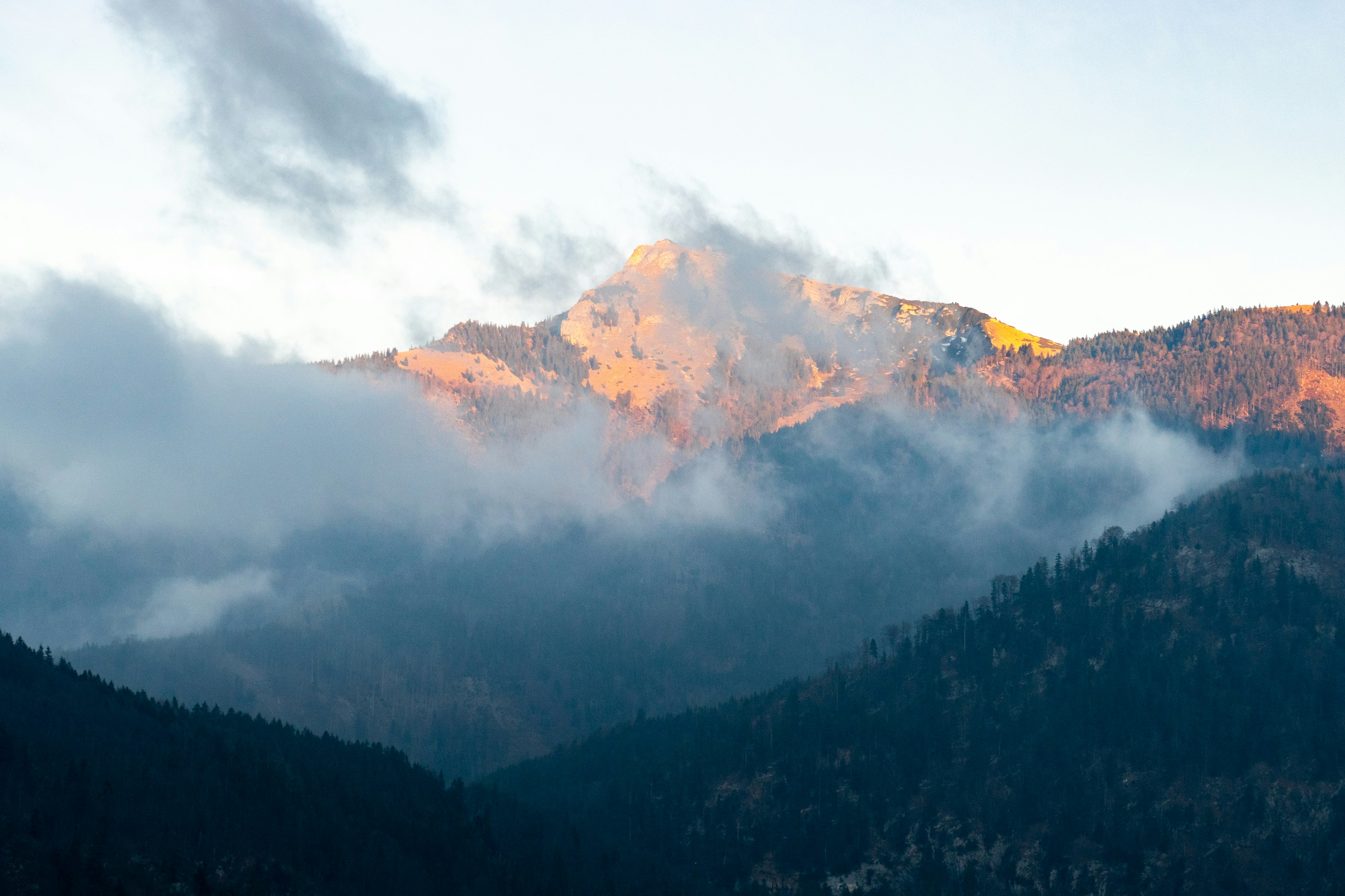 green trees near mountain under white clouds during daytime